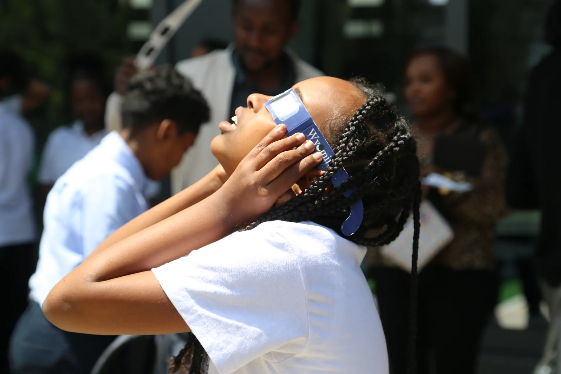 A schoolgirl looks up at the Sun through eclipse glasses