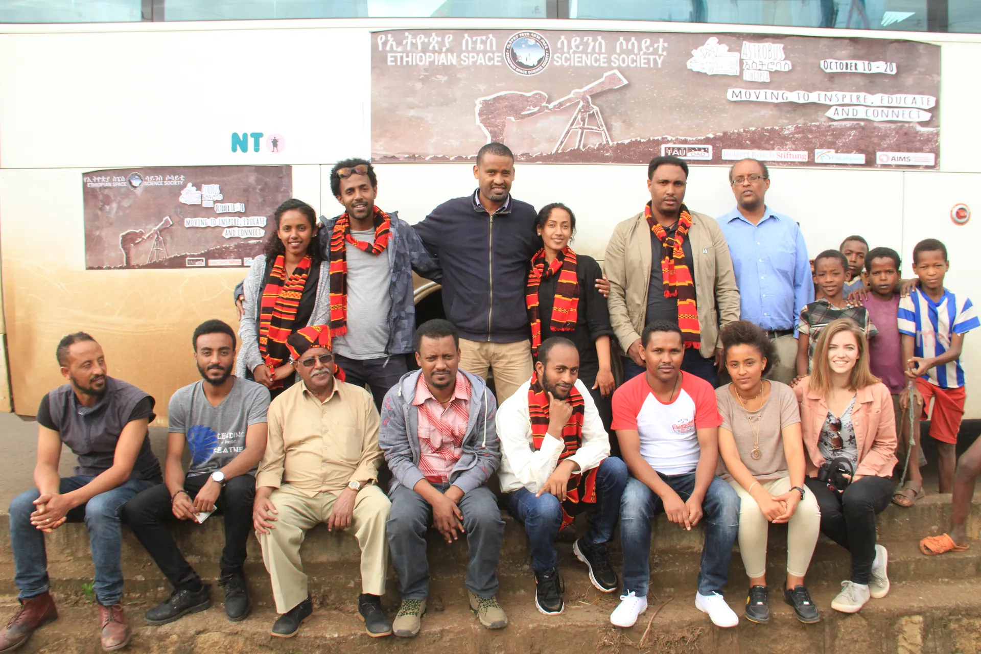 The team and local students in front of the bus