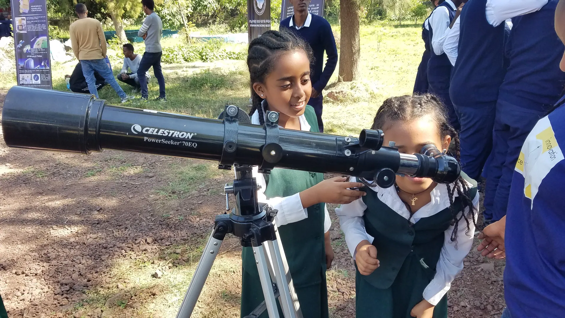 Two schoolgirls take turns at a telescope on the Astrobus tour