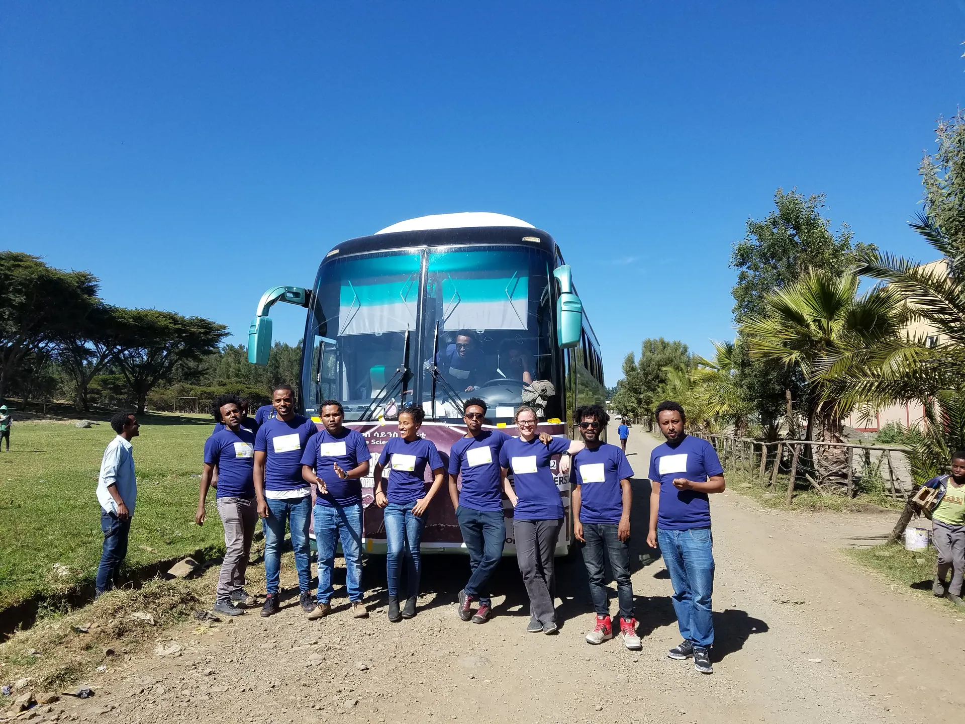 The team in front of the bus on a dirt road