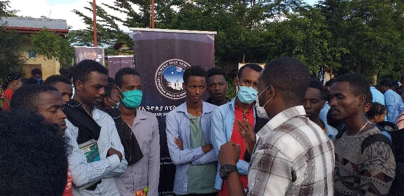 Young people in masks listen to a team member
