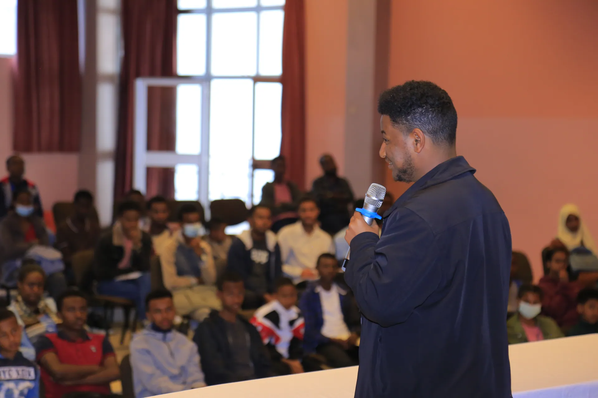 A speaker answers questions from a full hall at a public lecture